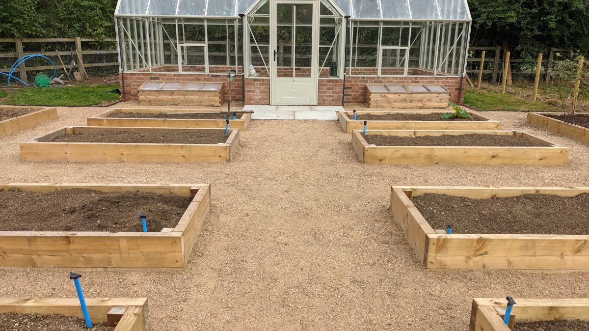 Kitchen garden. Brick greenhouse base, timber raised beds, gravel paths and fencing